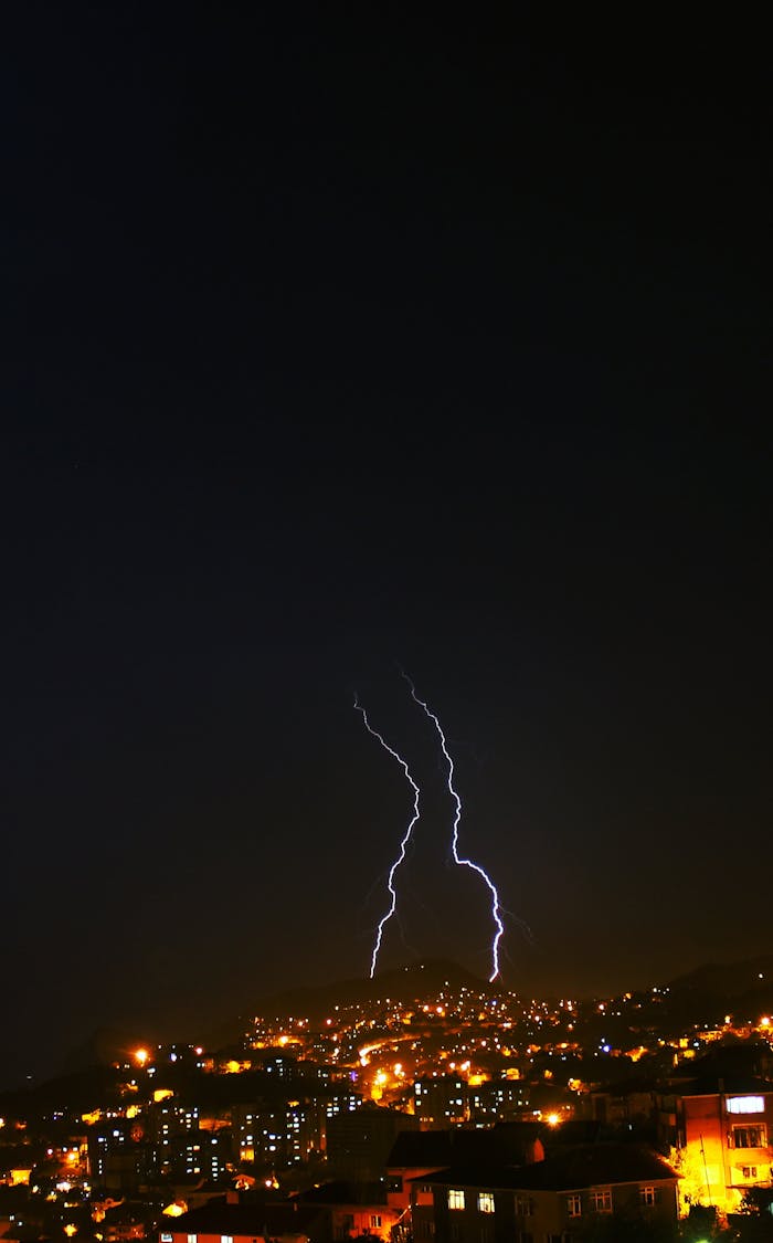 Dramatic lightning strikes illuminate an urban cityscape at nighttime, showcasing the power of nature.